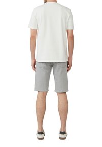 Witte katoenen T-shirt, lichtgrijze denim shorts met zichtbare achterzakken en witte schoenen met zwarte accenten. Casual pasvorm, korte mouwen, recht gesneden.
