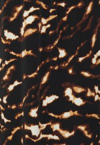 Motif abstrait d'imprimé animalier marron et beige sur tissu noir avec une surface douce et légèrement texturée.