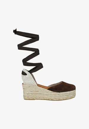 Alpargata cuña de ante marrón con suela de yute trenzado, puntera cerrada, contrafuerte tejido en el talón y largas cintas negras para atar al tobillo.