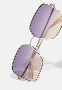 Purple-tinted square sunglasses with a gold metal frame, featuring clear accents and textured detail along the edges of the lenses.