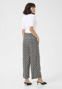 Flowy black and white patterned pants with an elastic waistband and side pockets. Paired with a fitted white top and heels.