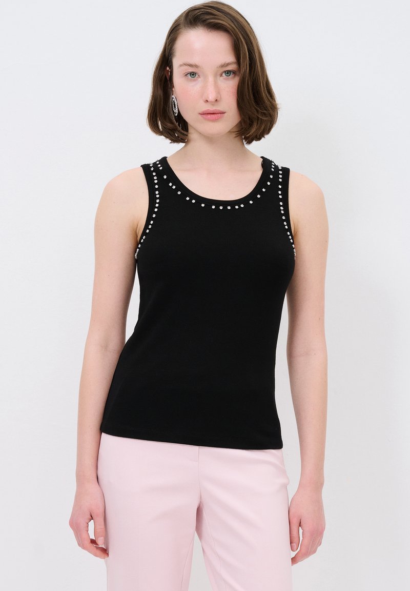 Zwart mouwloos topje met ronde halslijn, versierd met zilveren studs langs de schouders. Gladde textuur, aansluitend ontwerp.