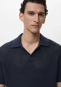 Polo shirt in maglia navy con una struttura a rete traspirante, colletto a coste e maniche corte. Presenta una chiusura con tre bottoni.