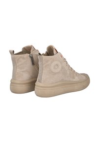 Zapatillas de deporte altas de ante beige con cordones, cremallera lateral, suelas de goma y un logotipo circular en el lado exterior de cada zapato.
