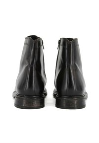 Stivaletti neri in pelle con finitura liscia, cerniere laterali e suola testurizzata. Presentano una punta rotonda e dettagli di cucitura minimi.