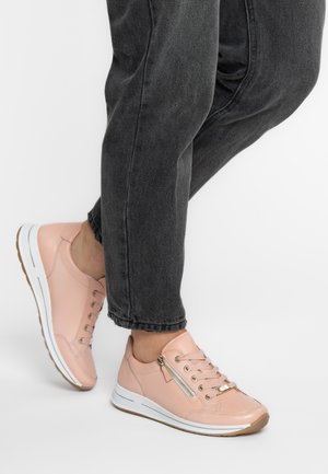 Rosa Leder-Sneaker mit Schnürsenkeln und seitlichem Reißverschluss, weißer Sohle, kontrastierenden beigen Akzenten und strukturierter Oberfläche. Getragen zu dunklen Jeans.