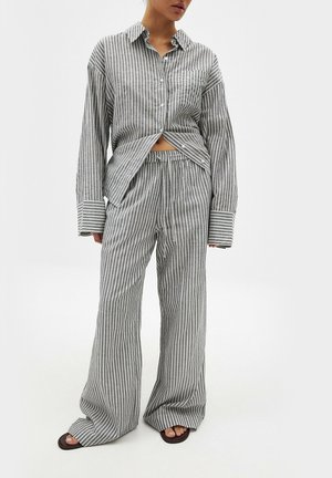 Chemise à rayures avec boutons et pantalon assorti en gris et blanc, coupe ample, fabriqué dans un matériau doux avec une texture lisse, présentant de larges poignets.
