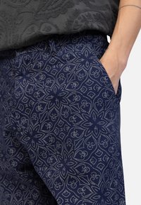 Navy blue patterned trousers with floral and geometric design. Made of soft fabric, featuring side pockets and a comfortable fit.