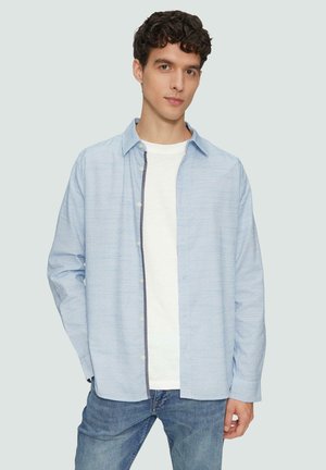 Lichtblauwe overhemd met een subtiele textuur, lange mouwen, gedragen over een wit t-shirt en blauwe jeans. Heeft een schoon, eenvoudig ontwerp.