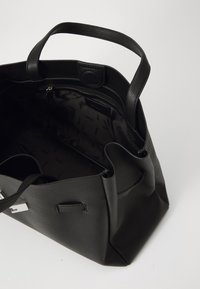 Svart lær tote bag, strukturert design, doble håndtak, topp glidelås, innerlomme, teksturert overflate og logo-detaljering.