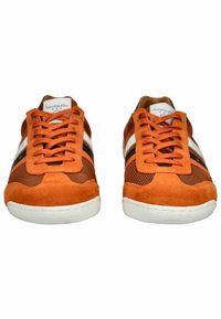 Oranžové semišové a síťované tenisky s bílými a černými pruhy, kulatou špičkou a plochými bílými gumovými podrážkami. Šněrování s hexagonálními očka.