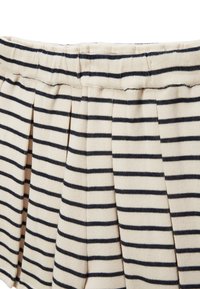 Shorts rayés avec une base beige clair et des rayures bleu marine foncé. Comprend des plis et une taille élastique pour le confort. Tissu en mélange de coton.