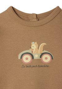 Brown cotton onesie featuring a graphic of a squirrel driving a pastel-colored car, with the text "En route pour aventure" below.