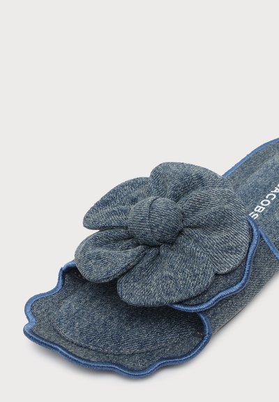 Chausson bleu denim à bout ouvert avec grande décoration fleur en tissu et bords festonnés sur la semelle.