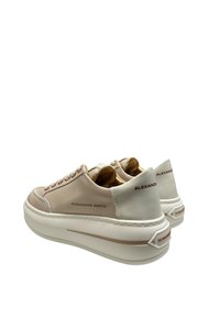 Beige og hvide sneakers med læder og tekstureret overdel, snøredetaljer, tyk sål og branding på siden og bagsiden.