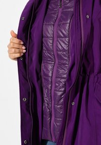 Giacca imbottita viola con un esterno liscio, dotata di fodera trapuntata, chiusura con zip e bottoni a pressione davanti.