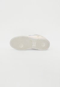 Teniska s hladkou bílou gumovou podrážkou, béžovými semišovými detaily a šedým textilním zdobením na boku. Kružnicový vzor podrážky.