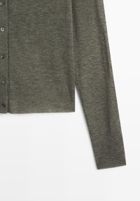 Grüne Strickjacke aus weichem Material. Verfügt über Knöpfe entlang der Vorderseite, gerippten Textur und einen geraden Schnitt mit seitlichen Schlitzen.