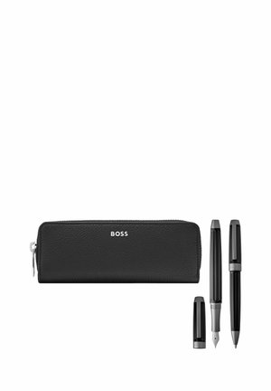 Czarny skórzany piórnik na zamek błyskawiczny z napisem "BOSS", obok którego znajduje się pióro wieczne bez nasadki oraz długopis z nasadką, na białym tle.