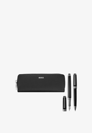 Estuche para lápices de cuero negro con cremallera y la etiqueta "BOSS", con una pluma estilográfica (sin tapa) y un bolígrafo con tapa junto a él sobre un fondo blanco.