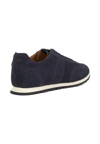 Suede sneakers in navy blue with a cream rubber sole, featuring a lace-up design and a round toe. Subtle branding on the heel.