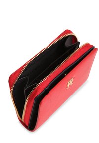 Κόκκινο πορτοφόλι από συνθετικό δέρμα με χρυστό φερμουάρ, μαύρη εσωτερική επένδυση και χρυσή λεπτομέρεια με λογότυπο στο μπροστινό μέρος. Δύο διαμερίσματα στο εσωτερικό.