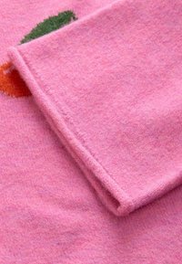Pink wool fabric featuring a soft, fuzzy texture. The design includes colorful carrot motifs in orange and green.