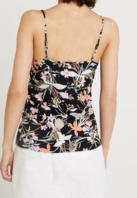 Czarna bluzka w kwiaty z cienkimi ramiączkami, ozdobiona mieszanką różowych, białych i pomarańczowych kwiatów. Gładki materiał i dopasowany krój.