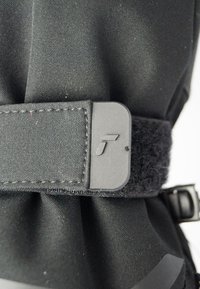 Zwarte stof met een gestructureerd oppervlak, voorzien van een plastic gesp en een klittenbandsluiting. Een subtiel logo is zichtbaar op de gesp.