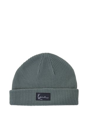 Grå strikket hue med opfoldet kant og et rektangulært sort mærke med hvid kursiv tekst foran.