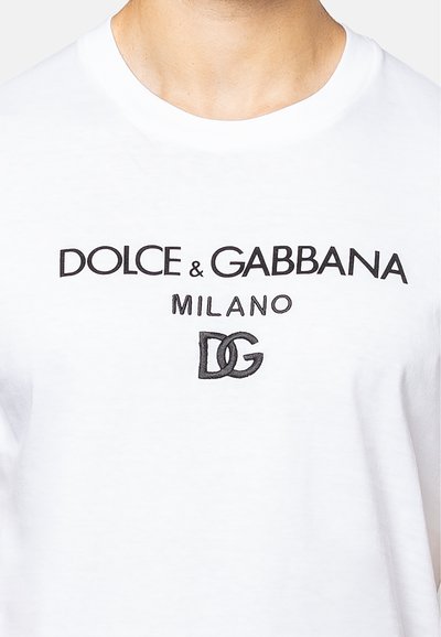 Witte katoenen t-shirt met zwart scriptlogo "DOLCE & GABBANA MILANO" en "DG" embleem aan de voorkant. Ronde halslijn en korte mouwen.