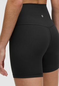 Shorts de tiro alto de color negro, con textura suave y un detalle del logo centrado en la parte trasera, presentando un diseño ajustado.