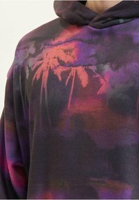 Felpa con cappuccio caratterizzata da un motivo gradiente in viola e arancione con un design di palme; realizzata in tessuto morbido con cappuccio regolabile.