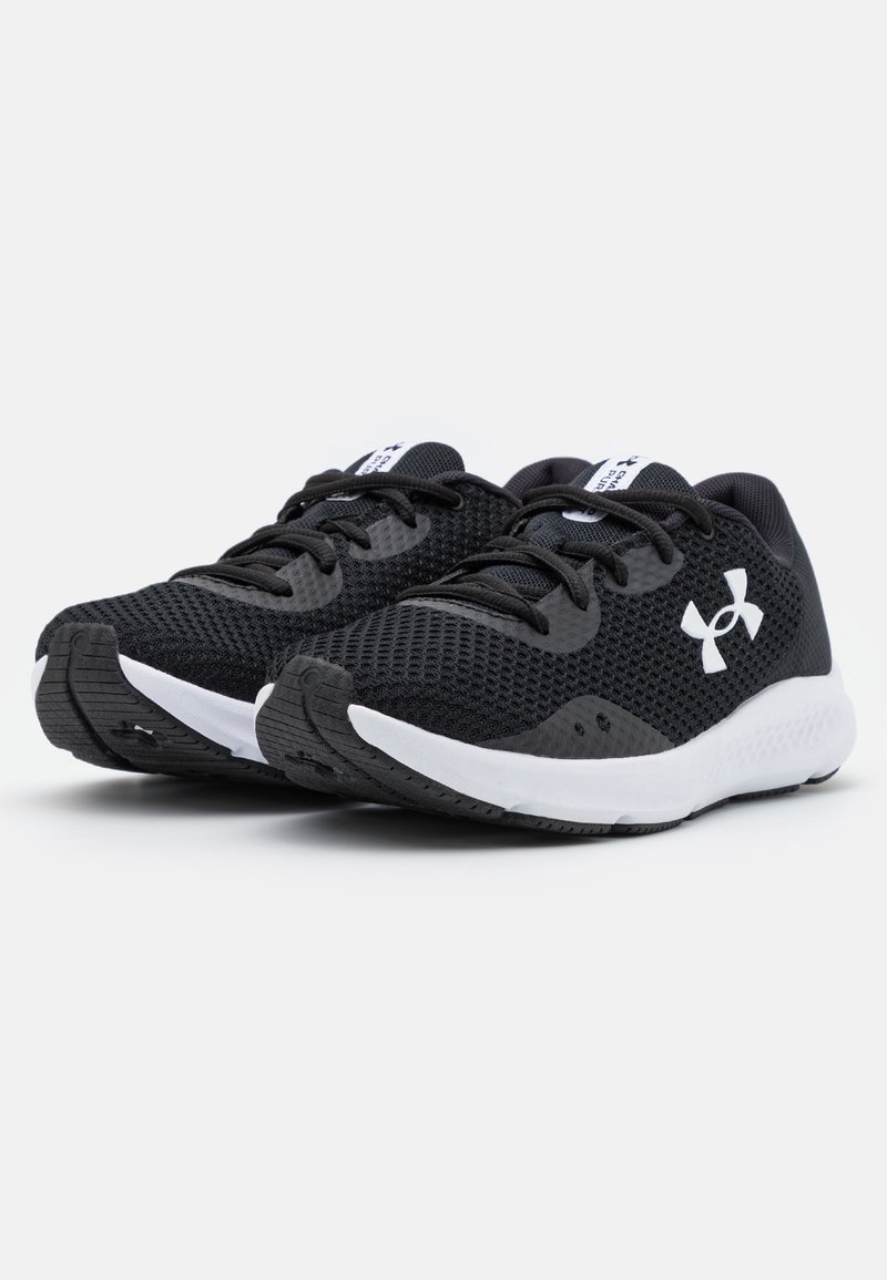 Zapatos deportivos negros con una parte superior de malla, punta redonda y suela intermedia blanca. Presentan cordones negros y un logotipo blanco prominente en el lateral.