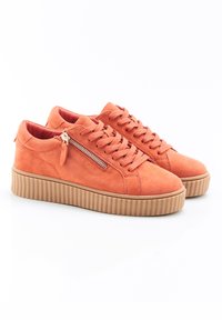 Baskets en daim orange avec une semelle en caoutchouc texturé, dotées d'une fermeture éclair sur le côté et de lacets traditionnels, conçues avec une silhouette basse.
