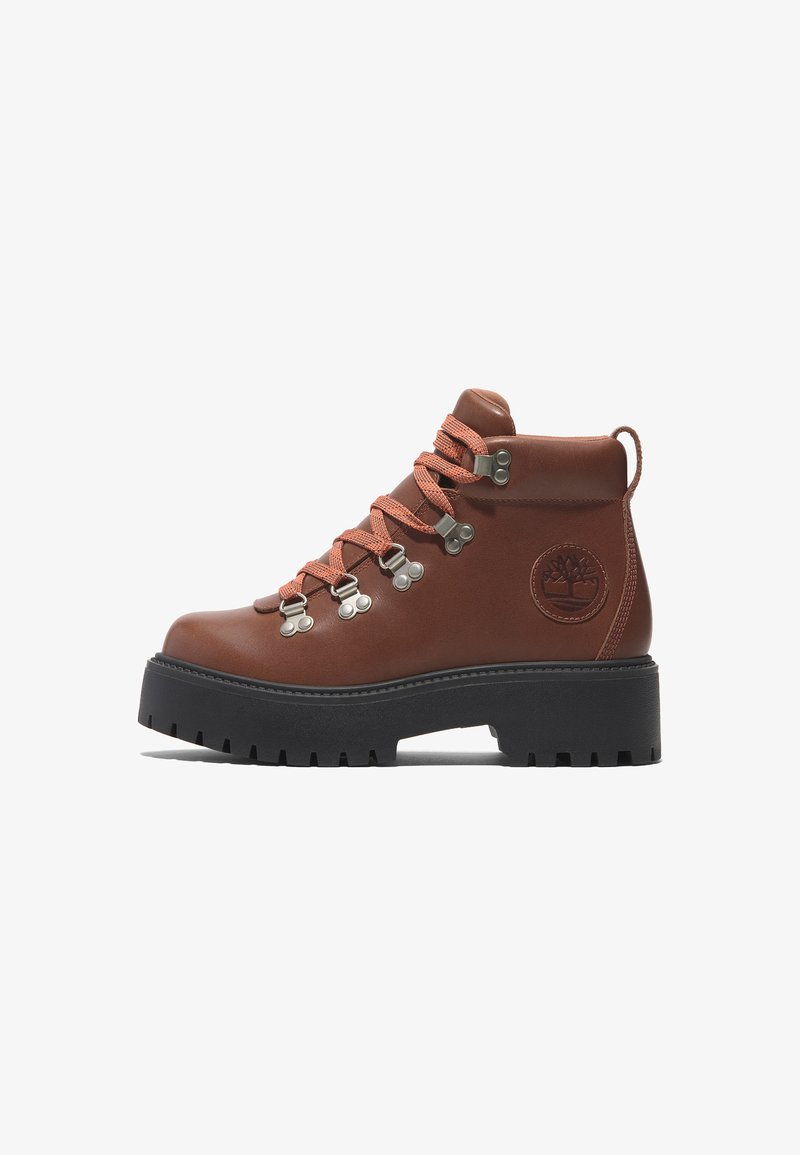 Braune Leder-Wanderstiefel mit orangefarbenen Schnürsenkeln, metallischen Ösen und einer Gummisohle. Verfügt über eine strukturierte Oberfläche und ein Logo an der Seite.