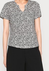 Top corto a maniche corte con motivo floreale in bianco e nero, caratterizzato da un scollo a V, una vestibilità comoda e una texture di tessuto morbida.