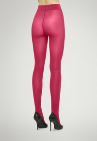 Calze trasparenti fucsia con una texture liscia, dotate di una vita ampia, abbinate a tacchi a spillo neri viste da dietro.