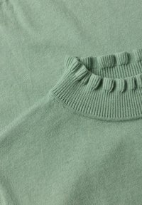 Pull tricoté vert clair doux avec un col montant à volants et une texture côtelée fine.
