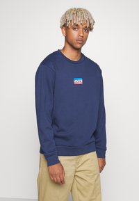Mörkblå sweatshirt i bomull med en liten Levi's-logotyp i röd och blå på bröstet. Långa ärmar och ribbade manschetter.