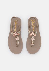 Brown flip-flops with a textured footbed, featuring a floral accent design in pastel colors. Made with yoga foam for comfort.