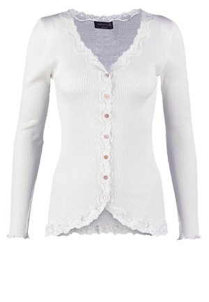 White ribbed cardigan with a scalloped lace trim, six pink buttons down the front, and long sleeves. Textured fabric with a fitted design.