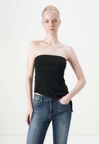 Black strapless top made of soft fabric, featuring a gathered design at the waist and a relaxed fit. Paired with light blue jeans.