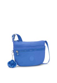 Borsa crossbody in tessuto blu con tasca con zip, tracolla regolabile e un charm a forma di scimmia fluffy blu attaccato alla cerniera.