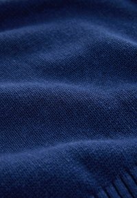 Gros plan sur un tissu tricoté doux de couleur bleu foncé montrant une texture fine et des plis subtils.