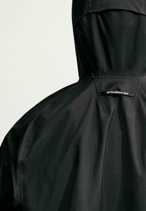 Black rain jacket with hood, showing back details and "All Conditions Gear" label on upper back.