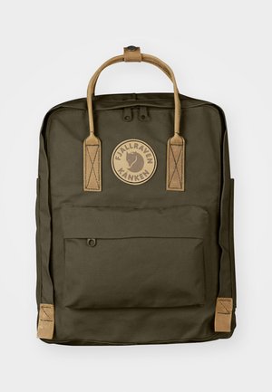 Mochila de tela verde oscuro con asas de cuero, un bolsillo frontal con cremallera y un logotipo circular con un emblema de zorro. Forma rectangular.