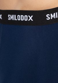 Pantaloni sportivi blu navy con una consistenza morbida e liscia e una cintura elastica nera con il nome del marchio "SMILODOX" in lettere bianche.