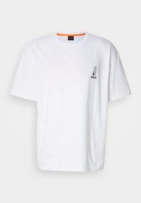 Weißes Baumwoll-T-Shirt mit kurzen Ärmeln, featuring ein kleines schwarz-graues Logo auf der linken Brust und einem orangen Akzent am Ausschnitt.