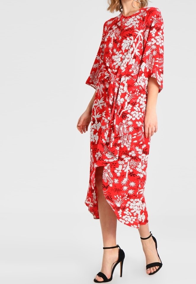 Robe midi florale rouge avec des manches courtes et une taille nouée. Comprend une fente latérale et une coupe ample. Motif floral blanc sur toute la robe.